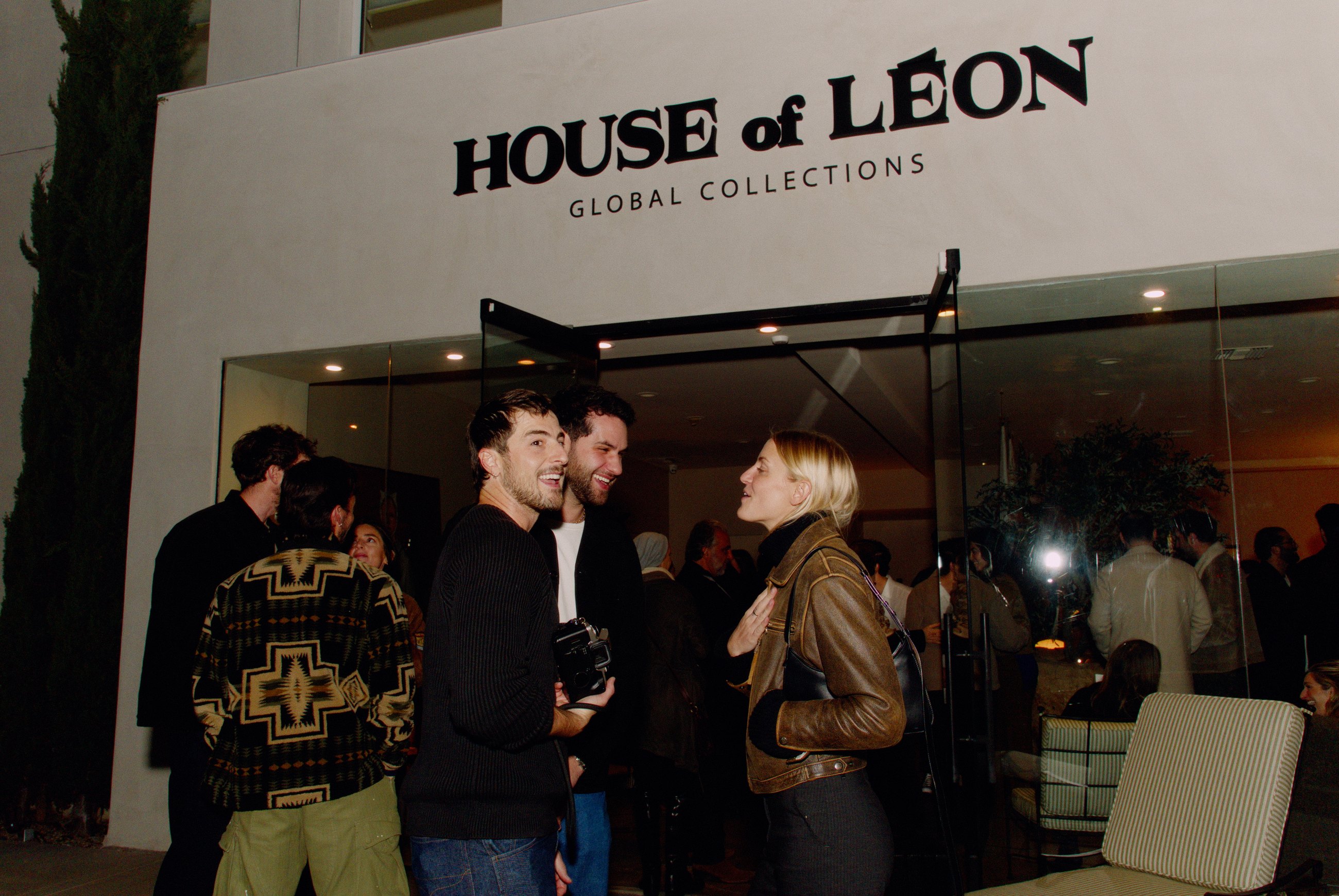 Guests talking beneath House of Leon exterior signage