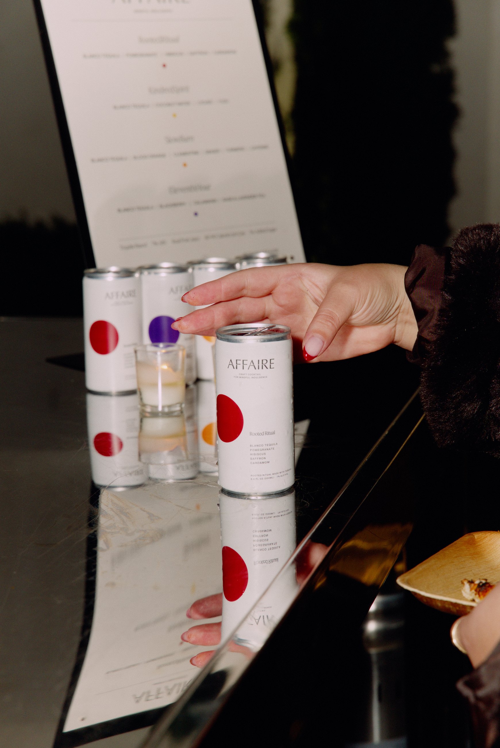 A hand reaching for a branded canned drink at an event bar