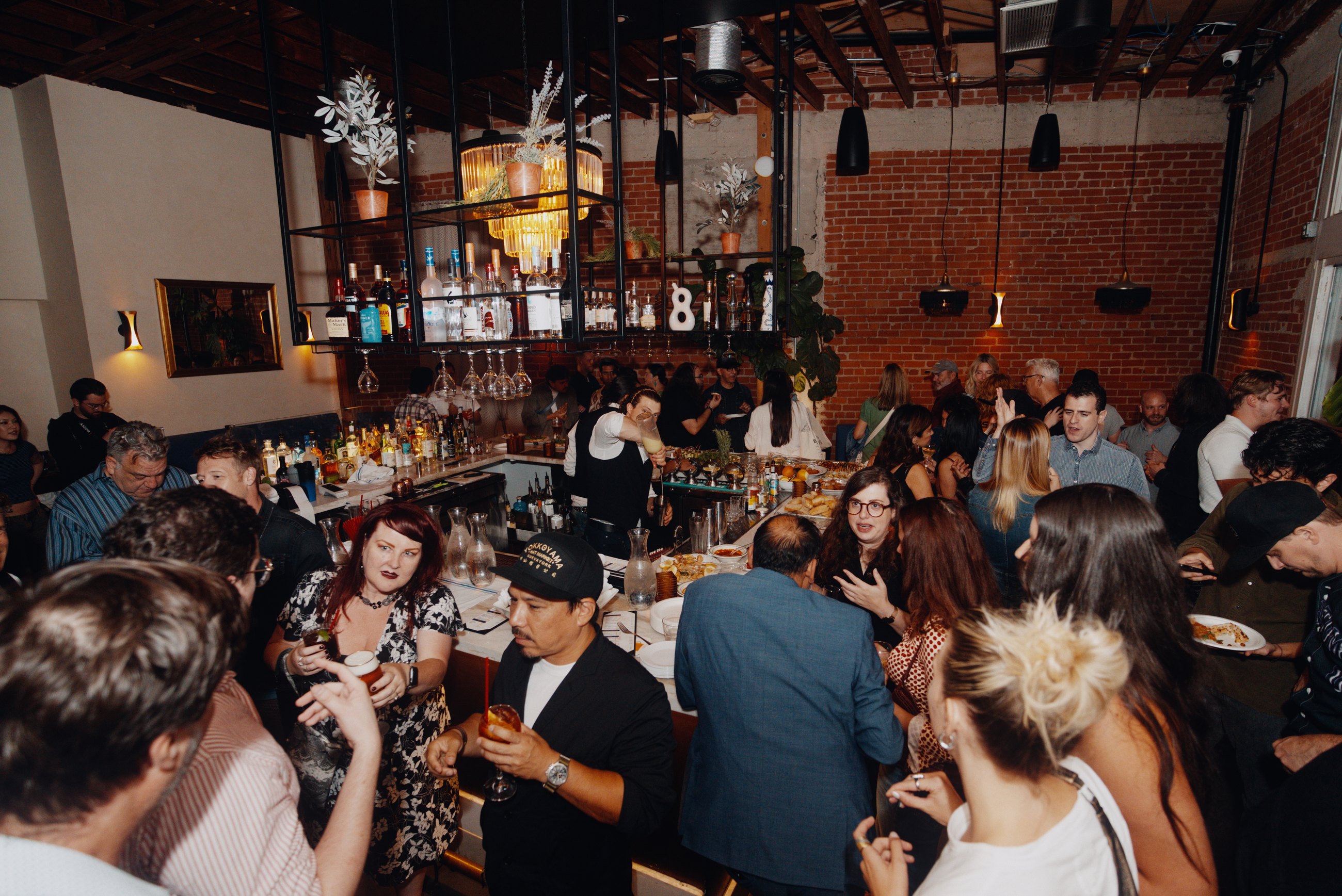 A packed restaurant event with guests around the bar