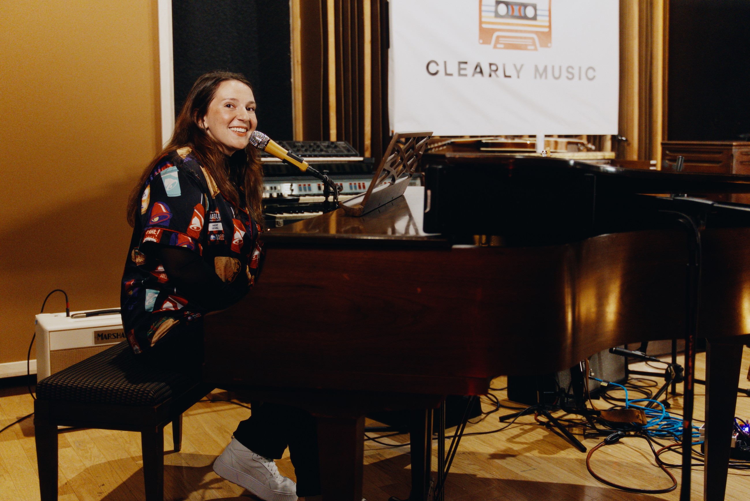A performer smiling at a piano during a creative event