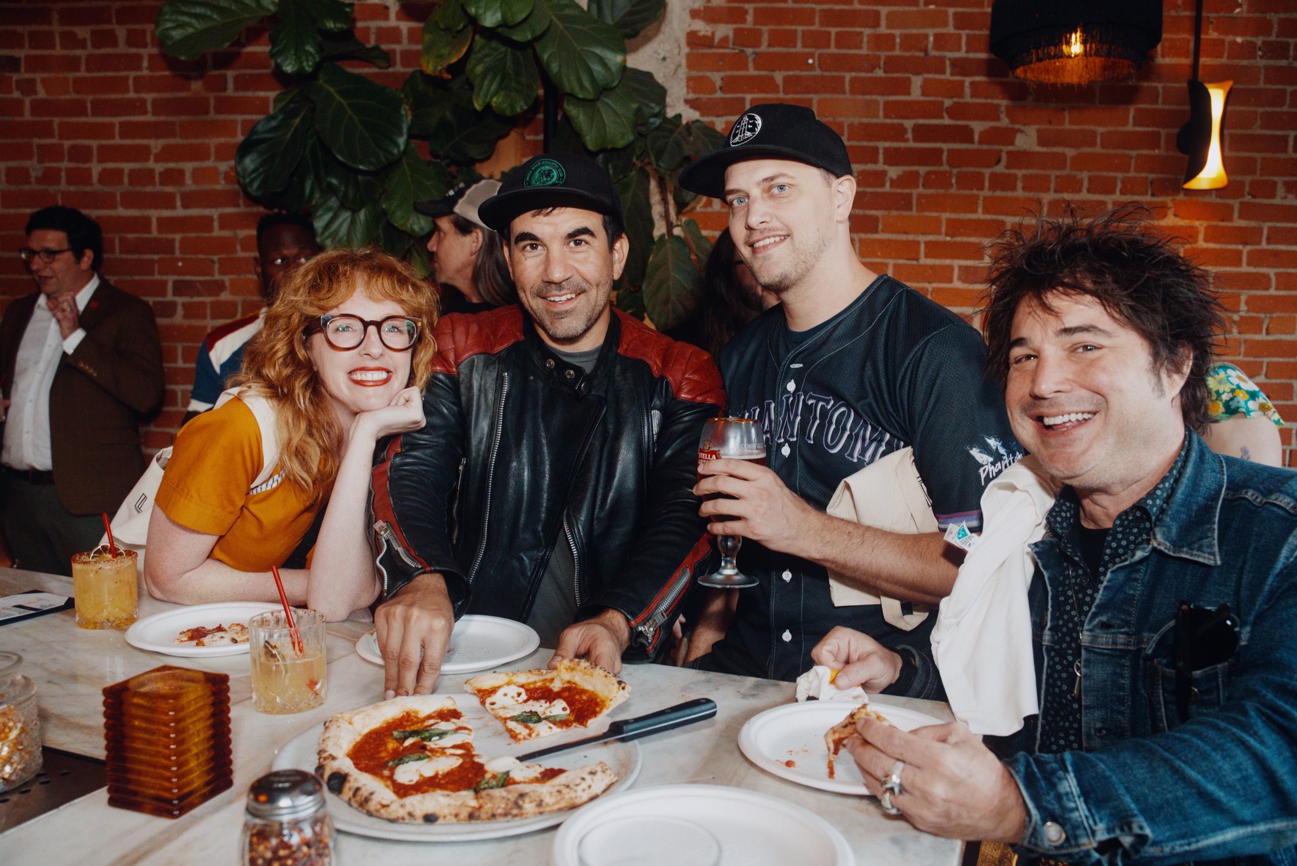 Guests gathered around pizza and drinks inside a lively social event